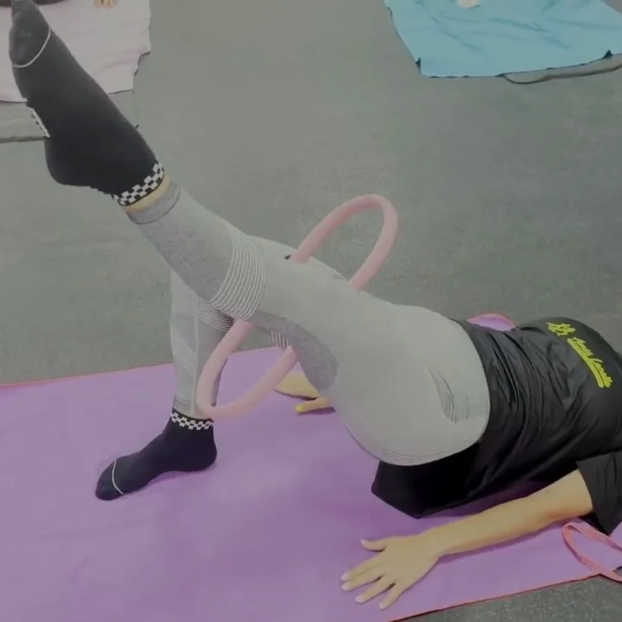 Clienta haciendo un ejercicio de pilates con aro (pilates ring) sobre una esterilla en el centro